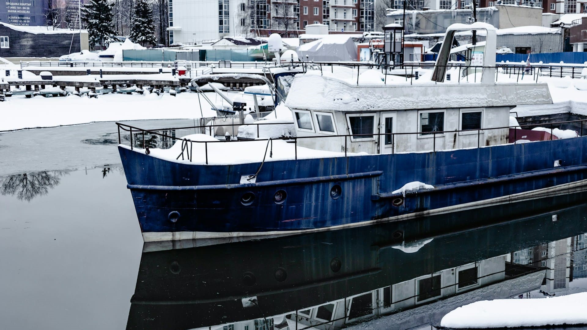 Boot in winterse haven met sneeuw op dek, toont noodzaak om je boot winterklaar te maken