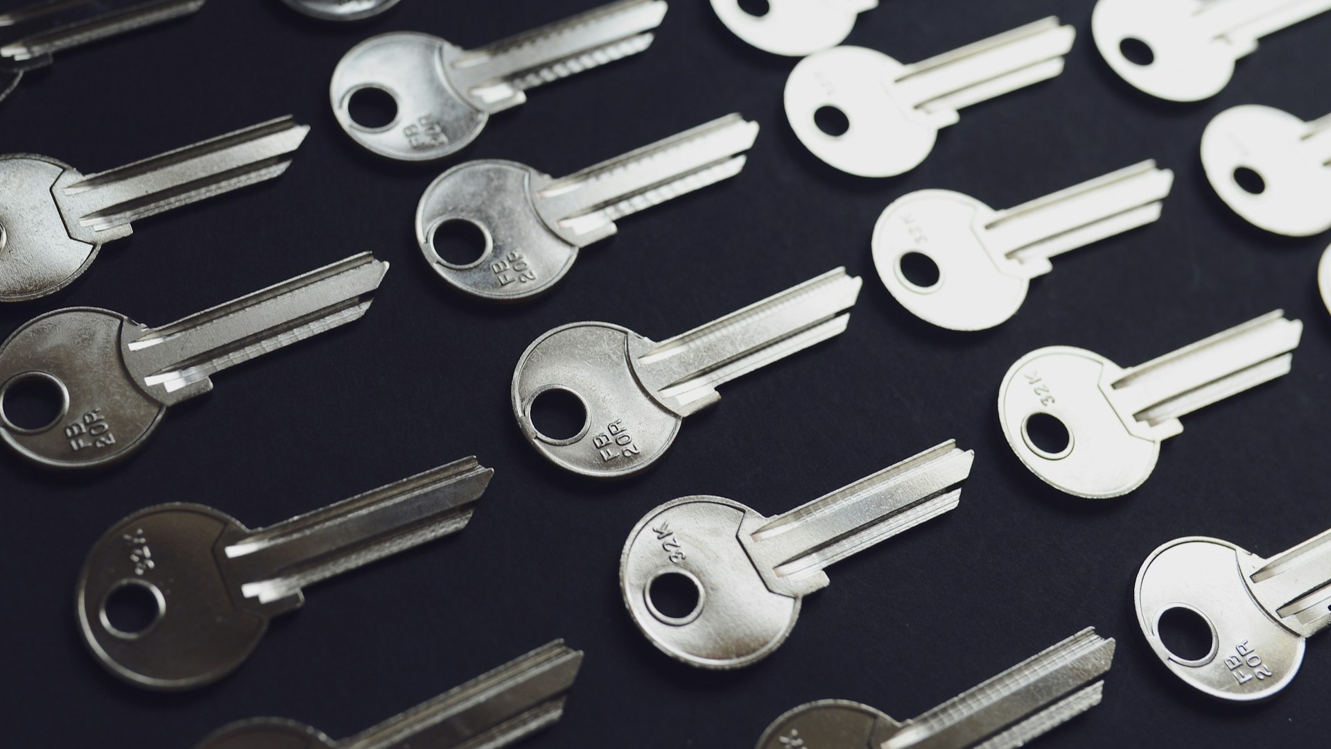Gelijkvormige sleutels als onderdeel van een masterkeysysteem liggen geordend op een donkere ondergrond.
