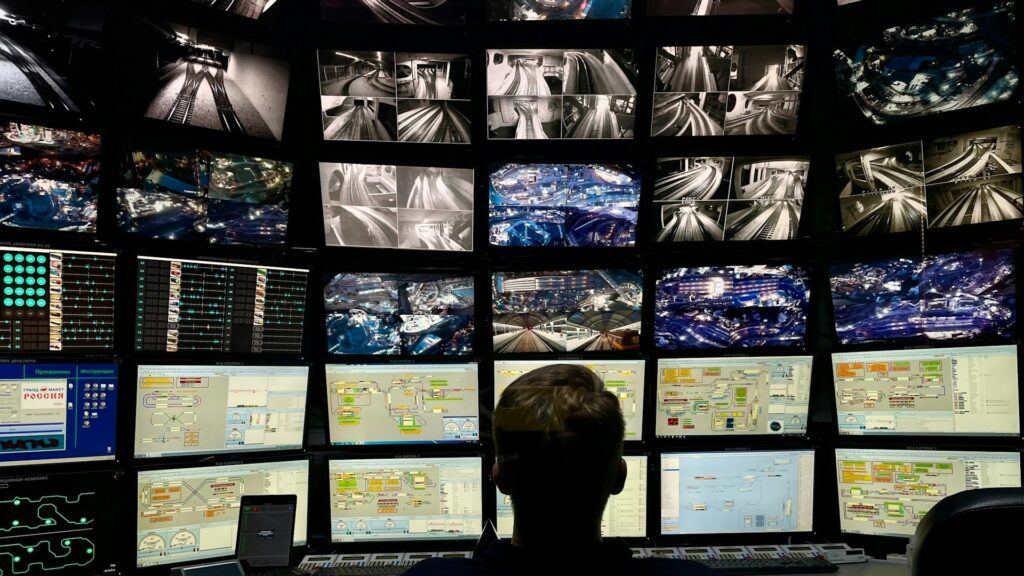 Beveiligingsmedewerker bewaakt toegangssystemen via meerdere schermen in een controlekamer binnen een masterkeysysteem.