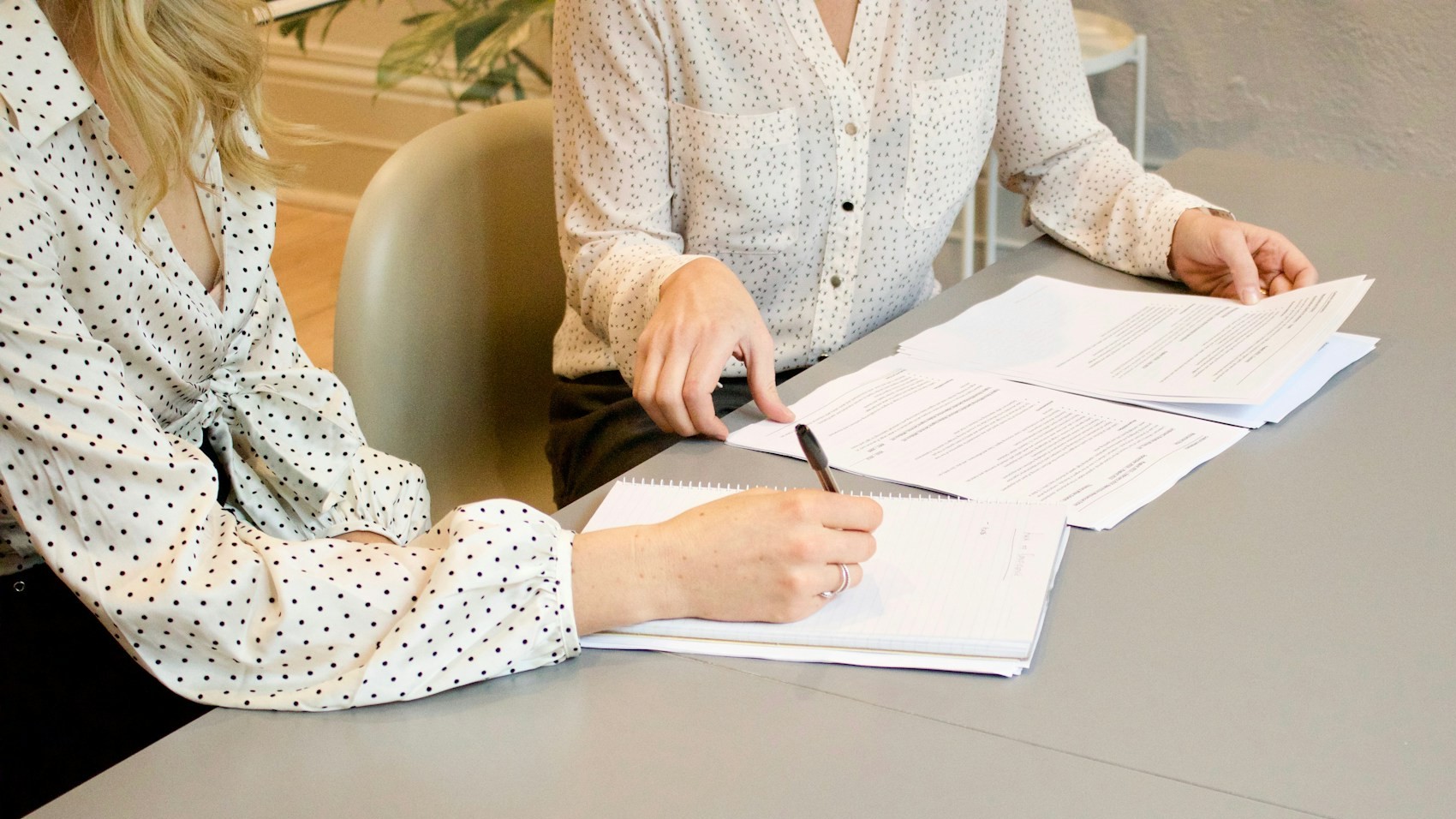 Twee vrouwen bespreken documenten aan tafel tijdens een bemiddelingsgesprek