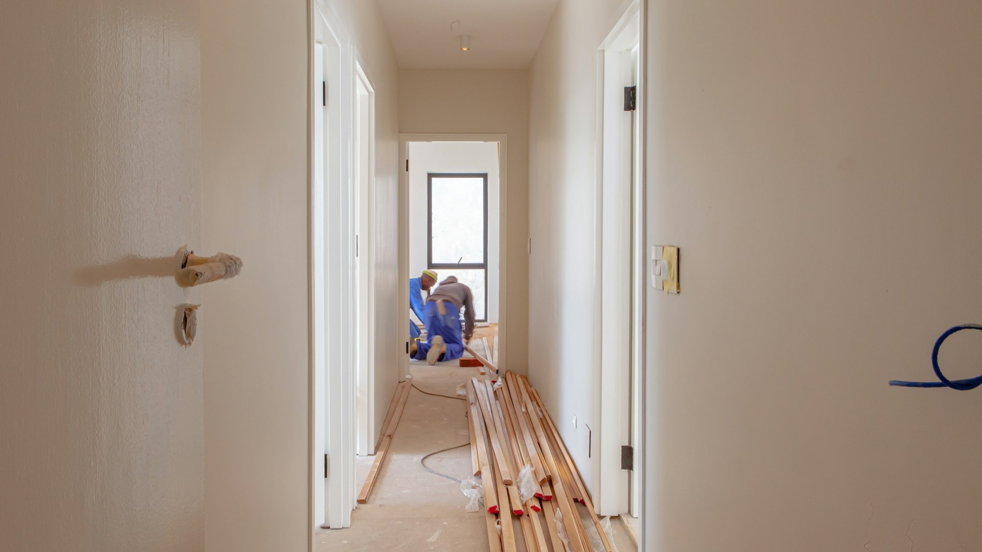 Werkmannen aan het klussen in een gang tijdens verbouwing, buren informeren voorkomt overlast
