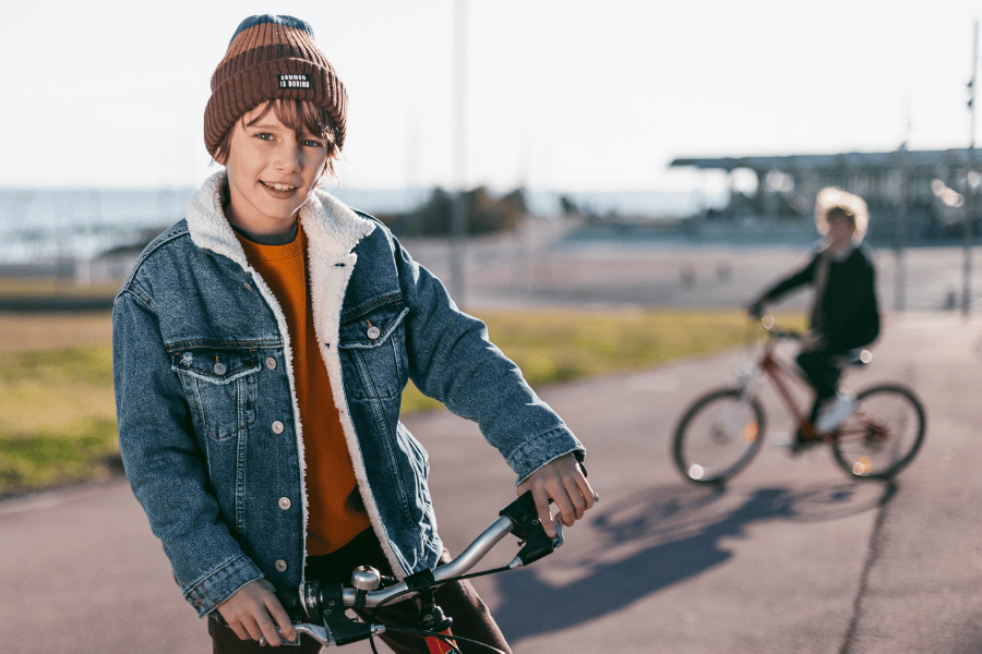 Kinderen grotere fiets buiten muts spijkerjas