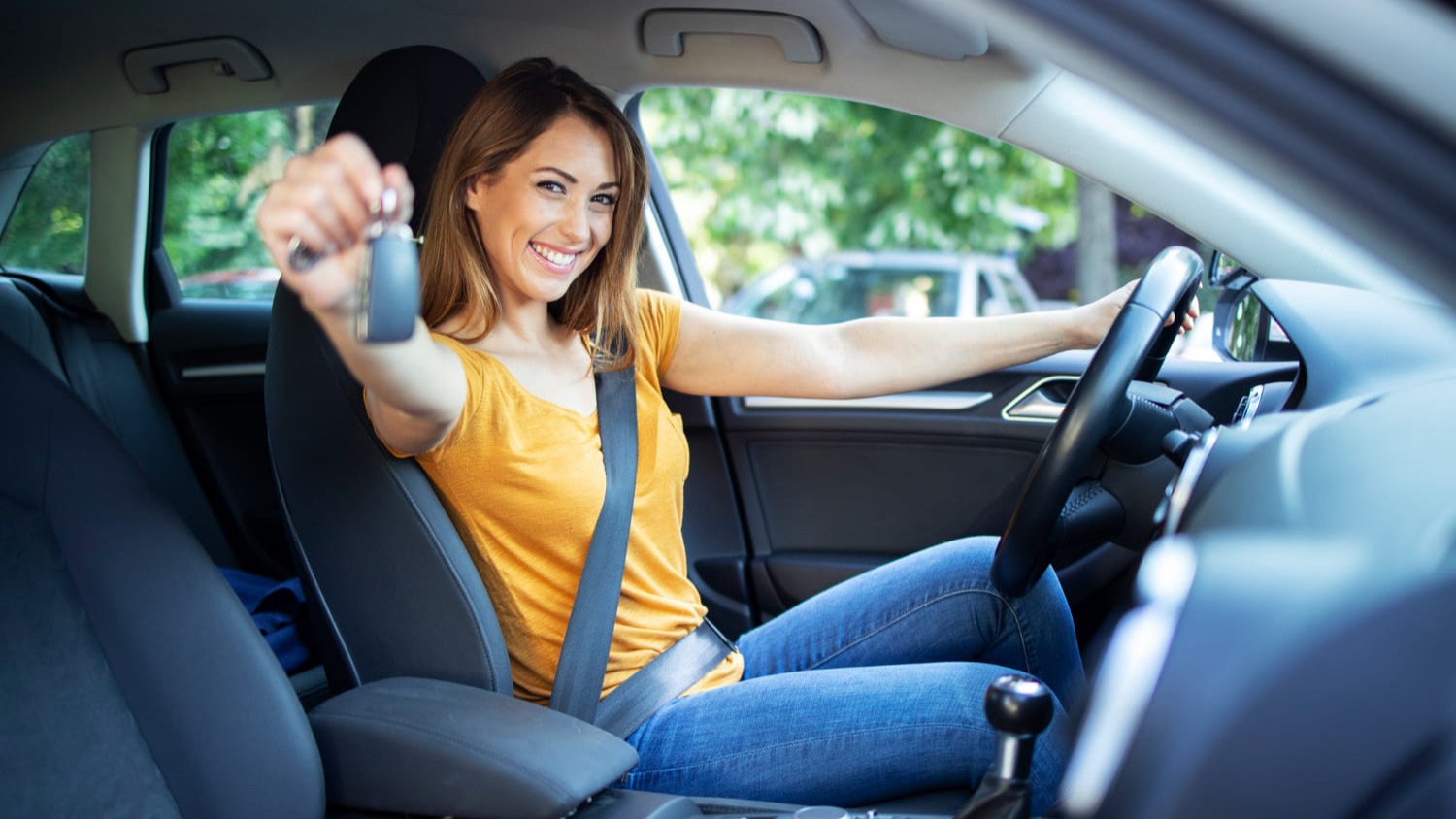 Blije jonge vrouw in auto toont autosleutel na succesvol examen met extra tijd theorie-examen.