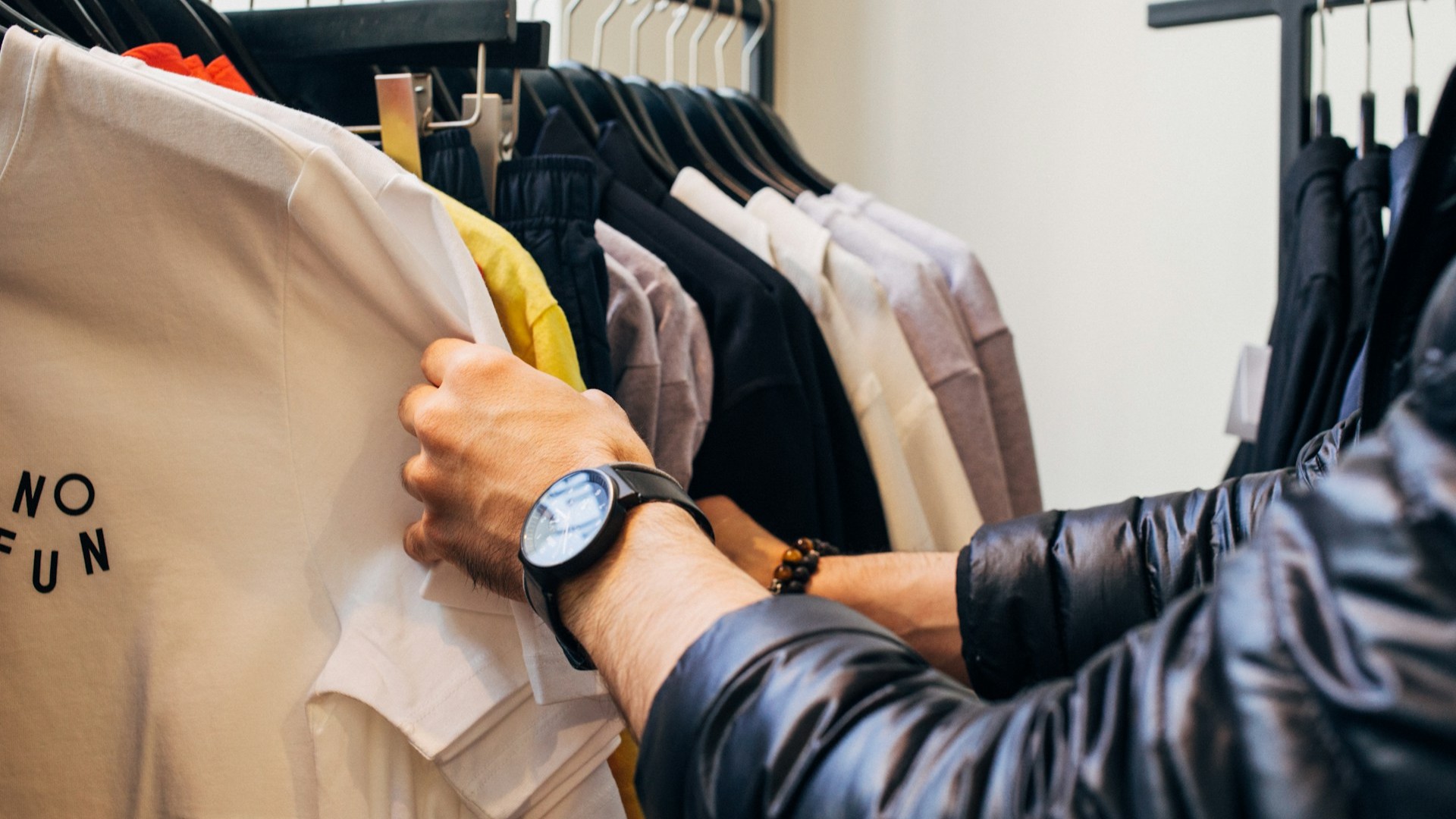 Pers bekijkt kleding in winkelrek bij keuze voor hergebruik na kleding wegbrengen