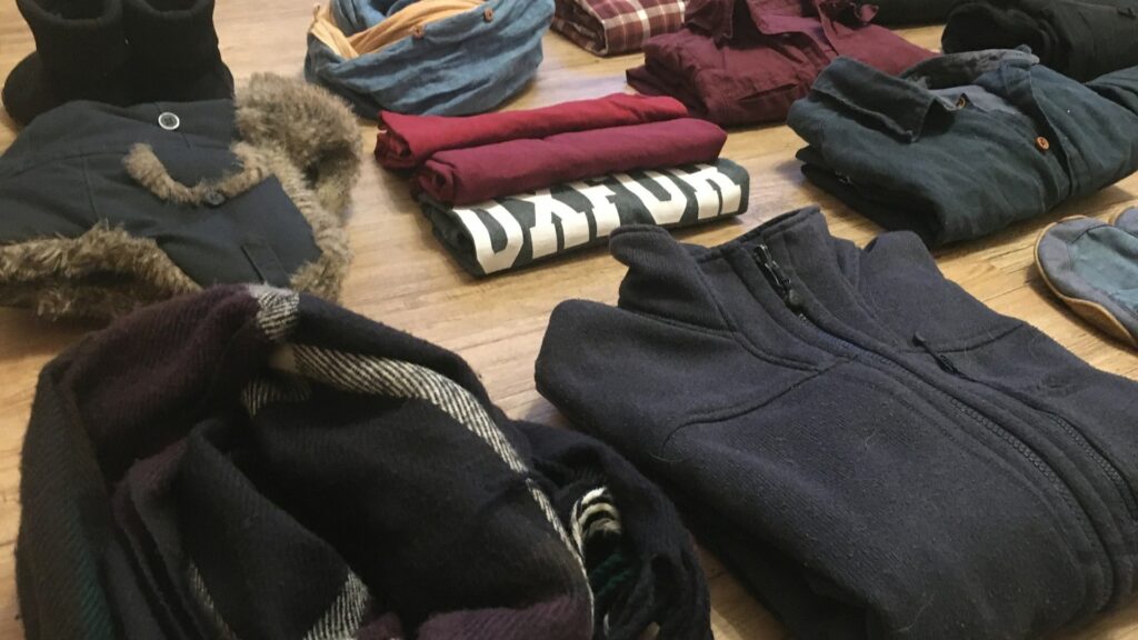 Opgevouwen kleding op vloer gesorteerd om te bepalen wat je kunt kleding wegbrengen