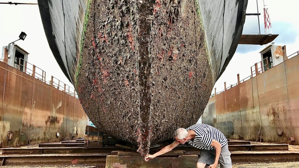 Sterk vervuilde scheepsromp met zeepokken tijdens onderhoud in droogdok voor zeepokken verwijderen boot