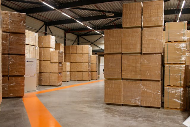 Een magazijn vol dozen met een looplijn tussen de dozen door
