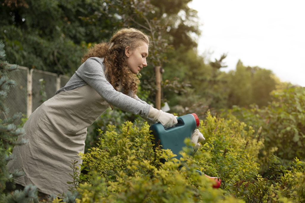 vrouw geeft planten water in de tuin